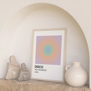 May include: A framed print with a gradient background of purple, pink, and orange with a blue and green circle in the centre. The print has the text "DISCO" and "HEX #CBB6D5 AURA" below the image.