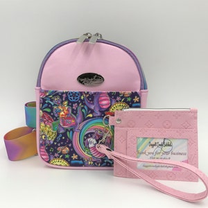 May include: A pink mini backpack with a colorful dragon print and a matching pink card holder with a zipper and a pink strap. The backpack has a silver zipper and a silver logo that says "Dragon Craft Studio". The card holder has a pink embossed pattern and the text "Dragon Craft Studio Thank you for your business Visit me on Etsy @ dragoncraftstudio.etsy.com dragoncraftstudio@gmail.com".