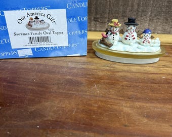 Nuestro tarro de vela ovalado Our America Candle con adorno familiar de muñecos de nieve en caja