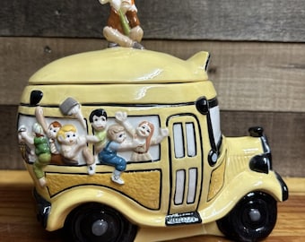 スクールバスの屋根に乗った運転手が「助けて」の看板を持ってクッキージャーを持っている