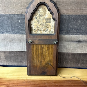 May include: A wooden cigar box with a picture of a Native American man on the front. The box has a sign that reads "Wooden Indian Cigars".