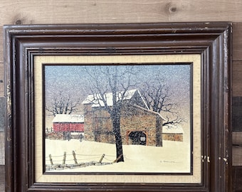 May include: A framed painting of a snowy winter scene with a red barn and a stone barn in the background. The painting is in a brown frame and has a white mat. The artist's signature is visible in the bottom right corner.