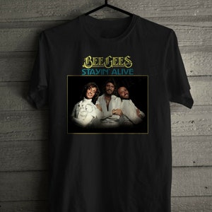 May include: Black t-shirt with a graphic of the Bee Gees band members and the text "Bee Gees Stayin' Alive".