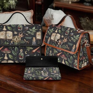 May include: Two black leather handbags with a dark green and brown floral print featuring mushrooms, herbs, and bottles. The smaller bag has a brown leather strap. The larger bag has a black leather strap and a matching black leather wallet.