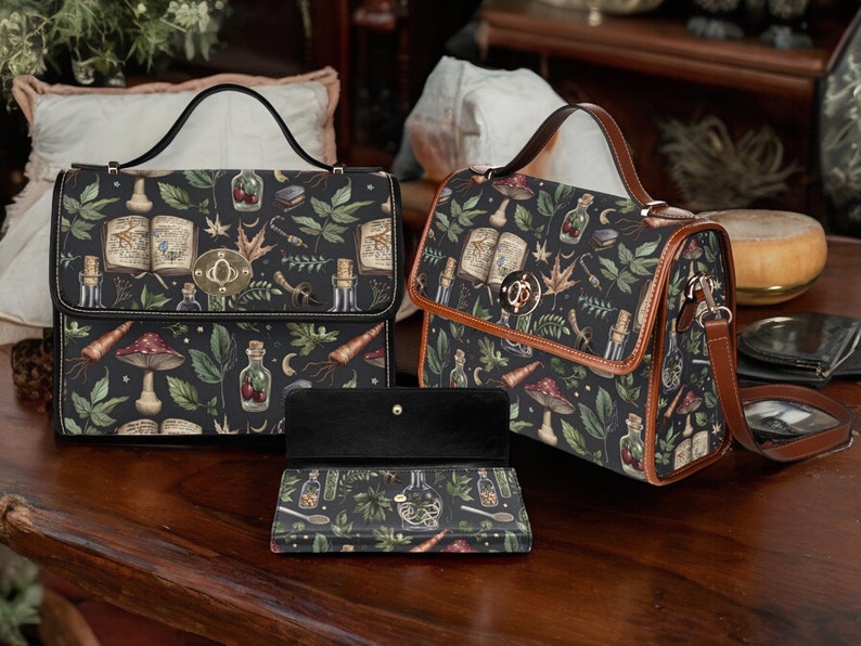 May include: Two black leather handbags with a dark green and brown floral print featuring mushrooms, herbs, and bottles. The smaller bag has a brown leather strap. The larger bag has a black leather strap and a matching black leather wallet.
