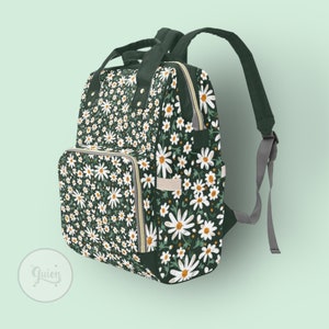 Peut inclure: Un sac &agrave; dos vert fonc&eacute; avec un motif floral de marguerites blanches. Le sac &agrave; dos a une poche avant zipp&eacute;e et des bretelles r&eacute;glables.