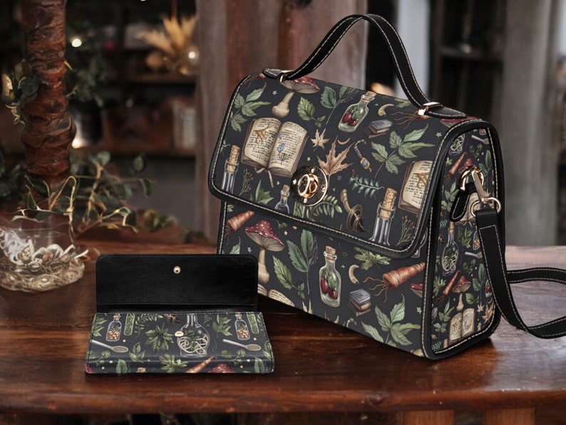 May include: A black satchel bag with a shoulder strap and a matching wallet. The bag and wallet feature a dark background with a whimsical pattern of books, mushrooms, herbs, and potion bottles.