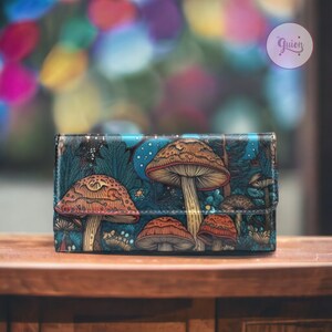 May include: A blue leather wallet featuring a colourful mushroom print. The mushrooms are red, orange and brown with white spots. The wallet has a flap closure and a small pocket on the front.