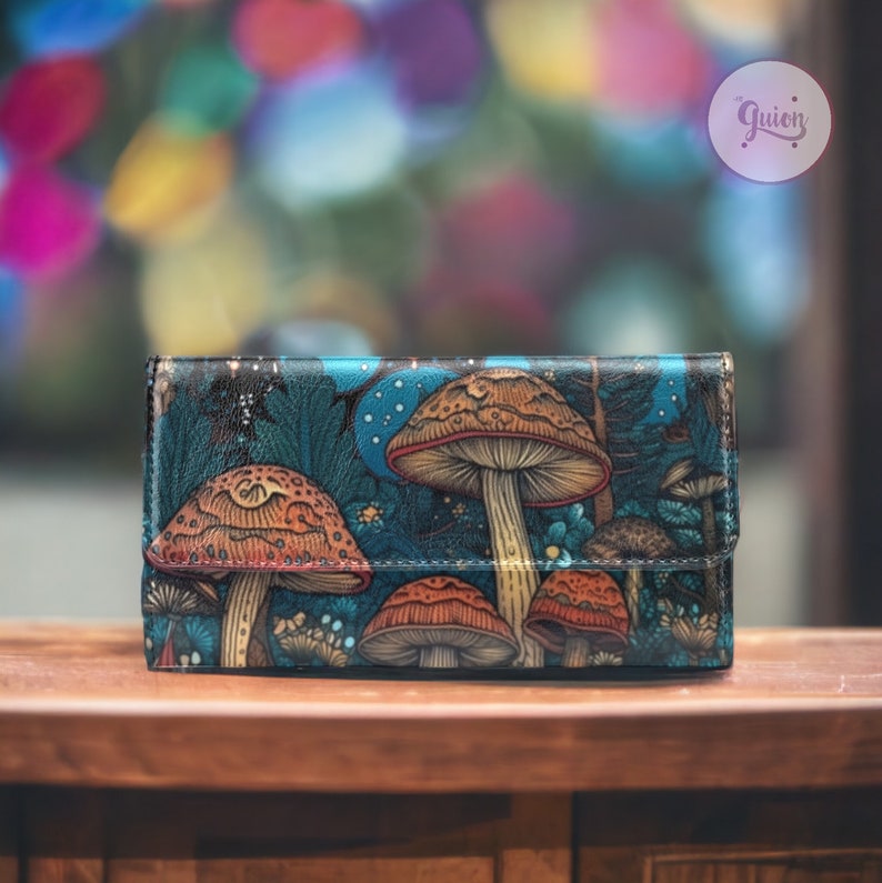May include: A blue leather wallet featuring a colourful mushroom print. The mushrooms are red, orange and brown with white spots. The wallet has a flap closure and a small pocket on the front.