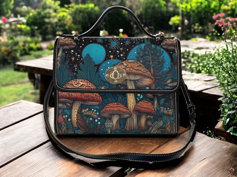 May include: A black leather satchel with a shoulder strap. The bag features a mushroom and forest scene design with blue and green colours.