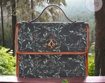 May include: A dark gray satchel handbag with a brown leather trim and a floral pattern. The bag has a top handle and a metal clasp.