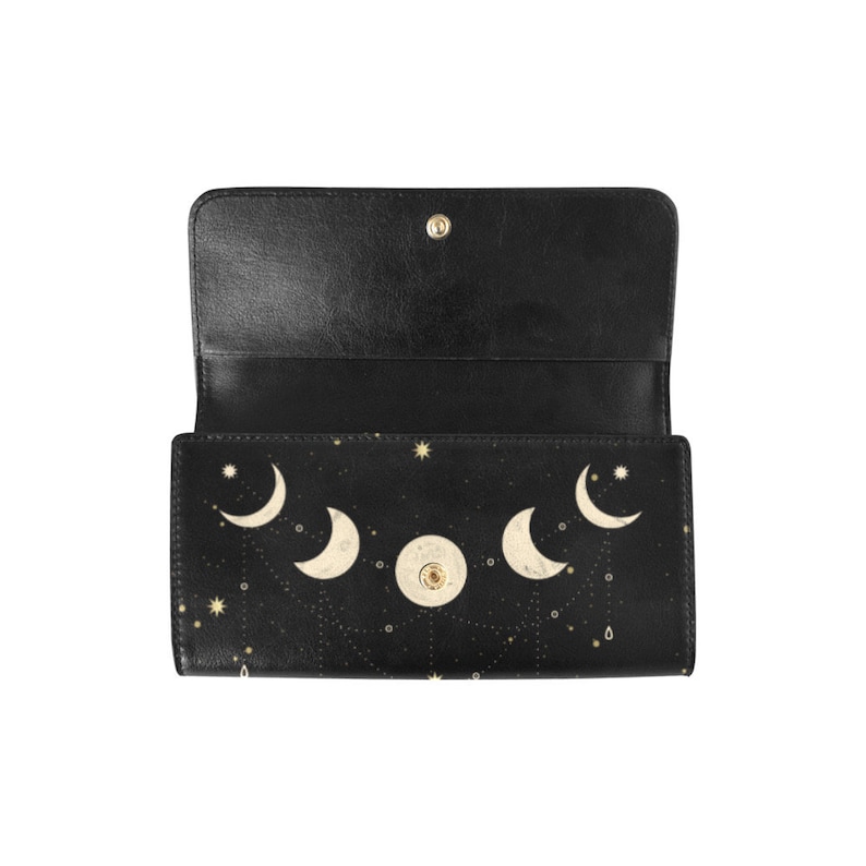 May include: A black leather wallet with a gold moon and stars design. The wallet is open and the inside is black.