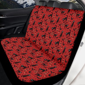 May include: Red car seat cover with a black and white Halloween pattern of black cats, pumpkins, bats, and stars.