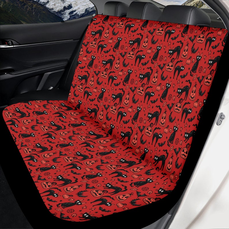 May include: Red car seat cover with a black and white Halloween pattern of black cats, pumpkins, bats, and stars.