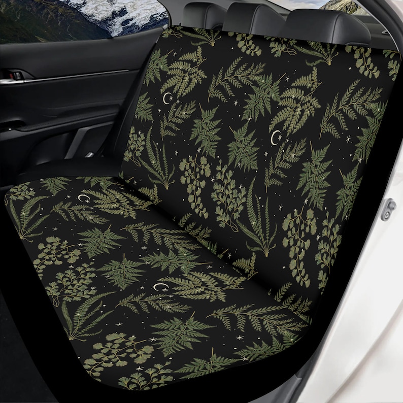 May include: Black car seat covers with a green fern and crescent moon pattern on a black background.