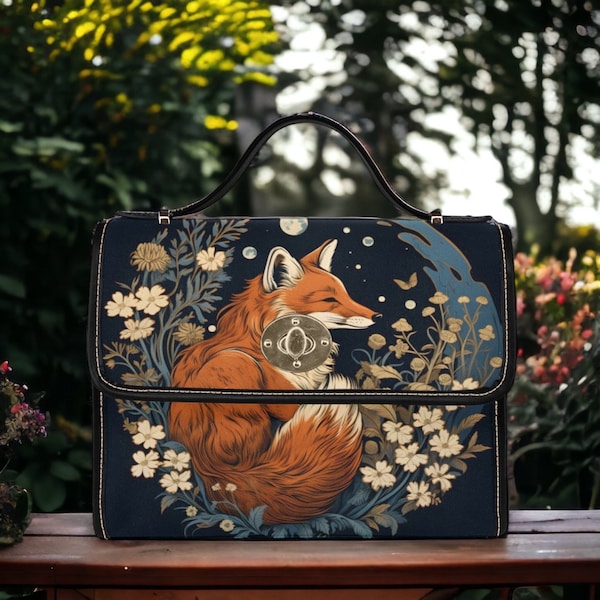 Könnte beinhalten: Eine dunkelblaue Handtasche mit einer Fuchs-Illustration und einem Blumendesign. Der Fuchs ist mit seinem Schwanz um seinen Körper gekräuselt. Die Tasche hat einen silbernen Verschluss und einen schwarzen Ledergriff.
