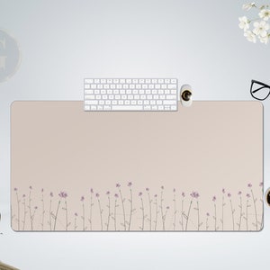 Peut inclure: Tapis de bureau rectangulaire beige avec un motif floral sur le bord inférieur. Un clavier blanc, une souris et une tasse de café sont sur le tapis. Des lunettes noires sont sur le côté droit.
