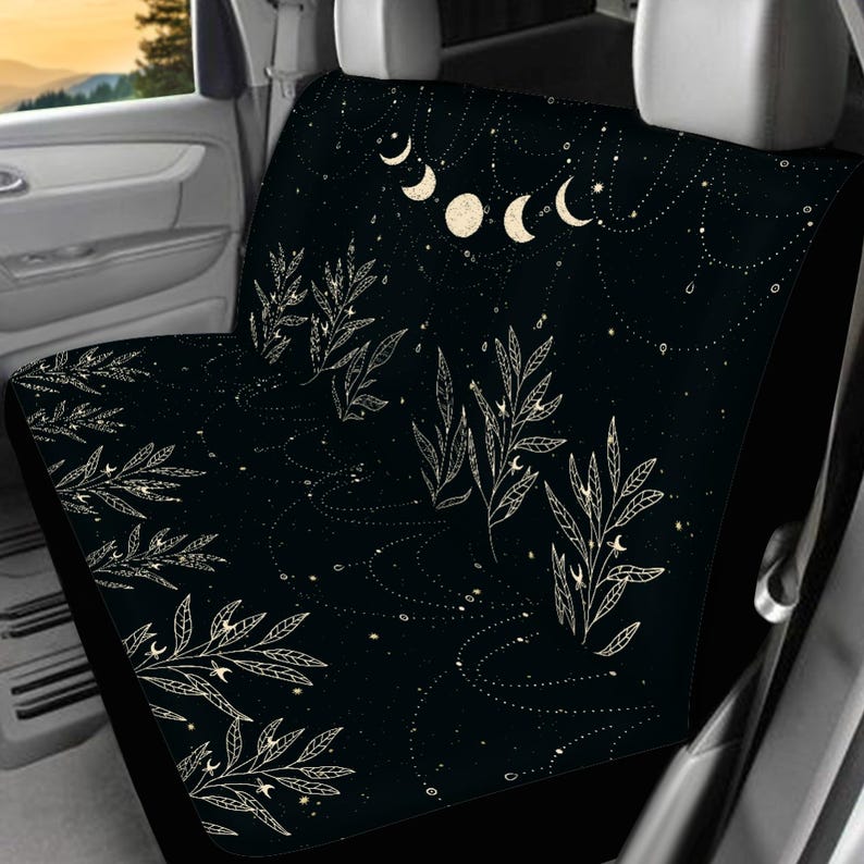 Puede incluir: Funda para asiento de coche negro con un dise&ntilde;o de luna y hojas blancas. El dise&ntilde;o presenta una luna creciente, estrellas y hojas sobre un fondo negro.