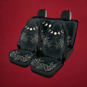 Puede incluir: Fundas para asientos de coche negras con un dise&ntilde;o celestial que presenta lunas blancas, estrellas y hojas sobre un fondo negro.