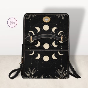 May include: Black leather backpack with a moon and stars design. The backpack has a flap closure with a gold buckle and a top handle.