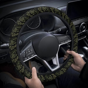 May include: A black steering wheel cover with a green and black floral pattern. The cover is made of a soft, comfortable material and is designed to improve grip and comfort while driving.