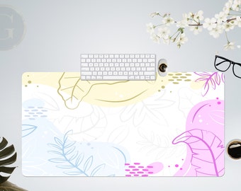 Könnte beinhalten: Rechteckige Schreibtischunterlage mit weißem Hintergrund und farbenfrohem, abstraktem Blumendesign. Das Design umfasst rosa, blaue und gelbe Formen mit Blättern. Eine weiße Tastatur, Maus und Kaffeetasse liegen auf der Unterlage.