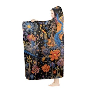 May include: A hooded blanket with a detailed floral and fantasy design. The blanket has a black background with illustrations of flowers, birds, and fantastical elements in orange, blue, and purple. The hooded design provides extra warmth and comfort, perfect for snuggling.