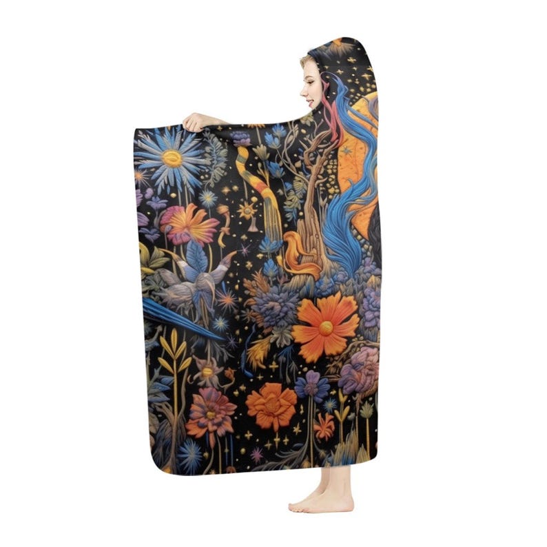 May include: A hooded blanket with a detailed floral and fantasy design. The blanket has a black background with illustrations of flowers, birds, and fantastical elements in orange, blue, and purple. The hooded design provides extra warmth and comfort, perfect for snuggling.