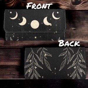 May include: A black leather wallet with a moon and stars design on the front and a leafy pattern on the back. The wallet has a zipper closure and a gold-colored zipper pull.