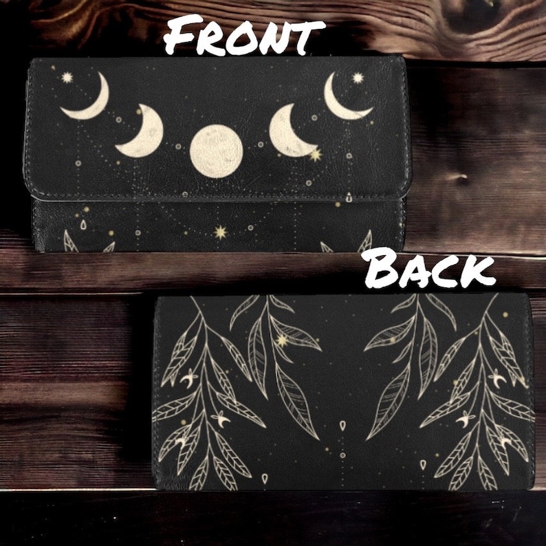 May include: A black leather wallet with a moon and stars design on the front and a leafy pattern on the back. The wallet has a zipper closure and a gold-colored zipper pull.