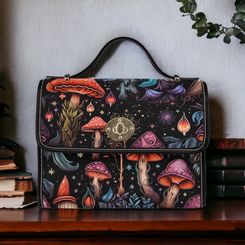 May include: A black leather satchel handbag with a silver clasp. The bag is decorated with a colorful mushroom and floral pattern on a dark background.