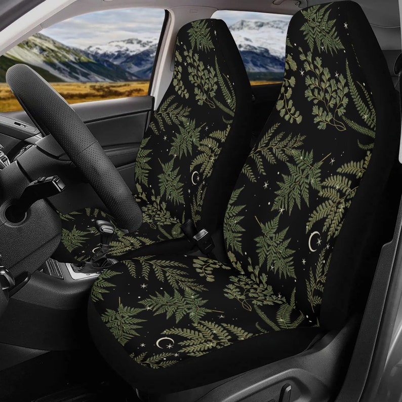May include: Two black car seat covers with a green fern and crescent moon pattern.