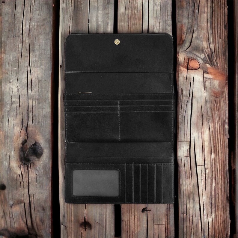 May include: A black leather wallet with multiple card slots and a billfold. The wallet is closed and lying on a wooden surface.