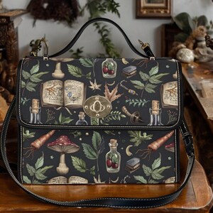 May include: A black leather satchel with a long shoulder strap. The bag has a dark green and brown floral print with images of mushrooms, herbs, and books.