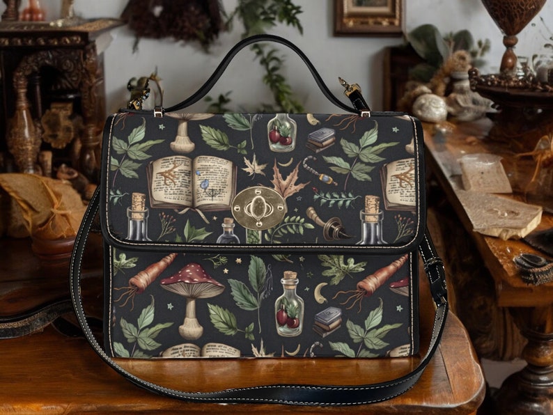 May include: A black leather satchel with a long shoulder strap. The bag has a dark green and brown floral print with images of mushrooms, herbs, and books.
