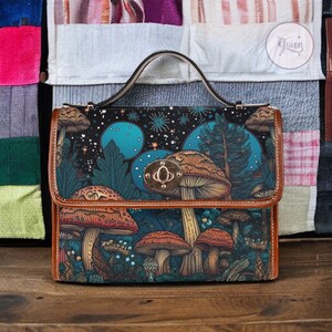 May include: A brown leather satchel with a mushroom and forest scene design. The bag has a top flap with a gold metal clasp and a brown leather handle.