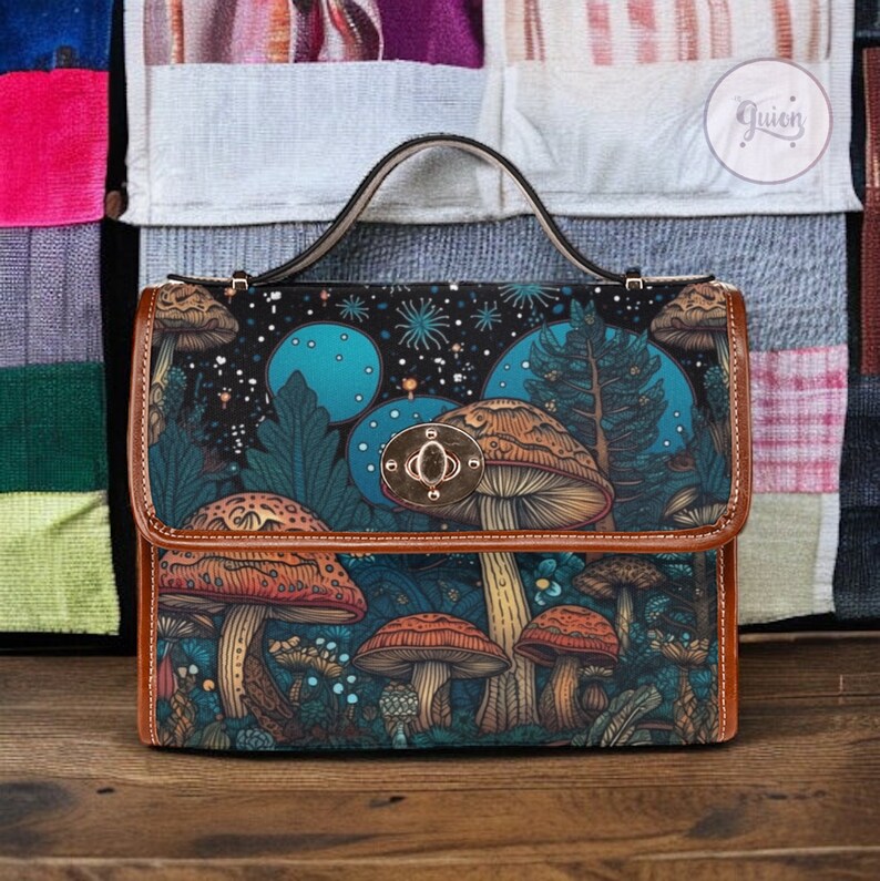 May include: A brown leather satchel with a mushroom and forest scene design. The bag has a top flap with a gold metal clasp and a brown leather handle.