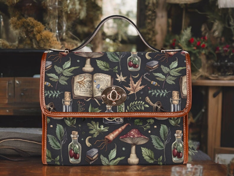 May include: A black satchel bag with a brown leather trim and a metal clasp. The bag is decorated with a whimsical pattern of mushrooms, leaves, bottles, and other botanical elements.