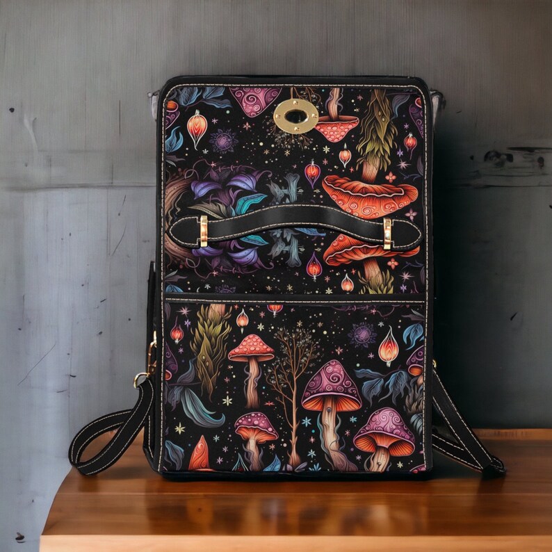 May include: A black leather backpack with a mushroom and floral pattern. The backpack has a top handle and adjustable straps. The pattern is in shades of pink, purple, orange, and green.