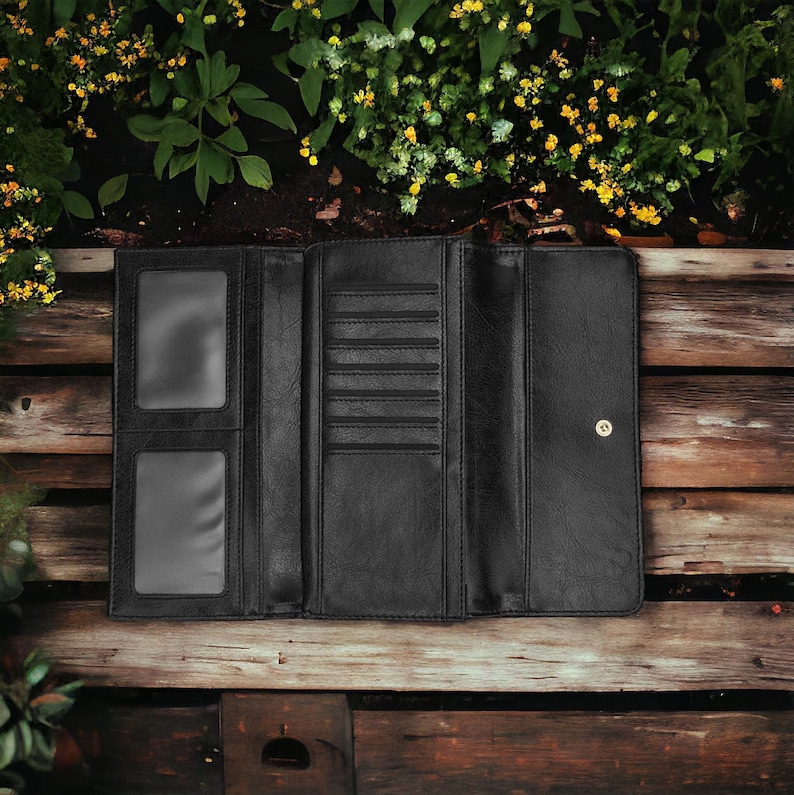 May include: A black leather wallet with multiple card slots and a billfold. The wallet is open and lying on a wooden surface.