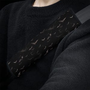 Pode incluir: Capa de cinto de seguran&ccedil;a de carro preto com um padr&atilde;o de morcegos brancos em fundo preto.
