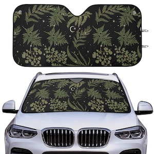 May include: A black car sunshade with a pattern of green ferns and white crescent moons on a black background.
