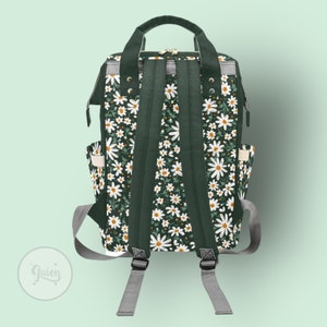 Peut inclure: Un sac &agrave; dos vert fonc&eacute; avec un motif floral de marguerites blanches. Le sac &agrave; dos a des bretelles r&eacute;glables et une fermeture &agrave; glissi&egrave;re.