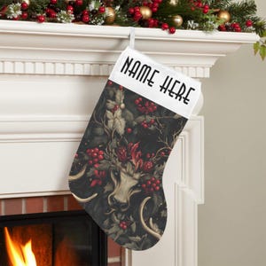 May include: A Christmas stocking with a dark background featuring a deer design with antlers, red berries, and floral elements. The top of the stocking has the text "NAME HERE" in bold, black letters.