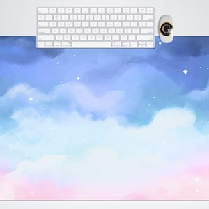 May include: A watercolor desk mat with a blue, pink, and white sky with clouds and stars. The mat is perfect for adding a touch of whimsy to your workspace.