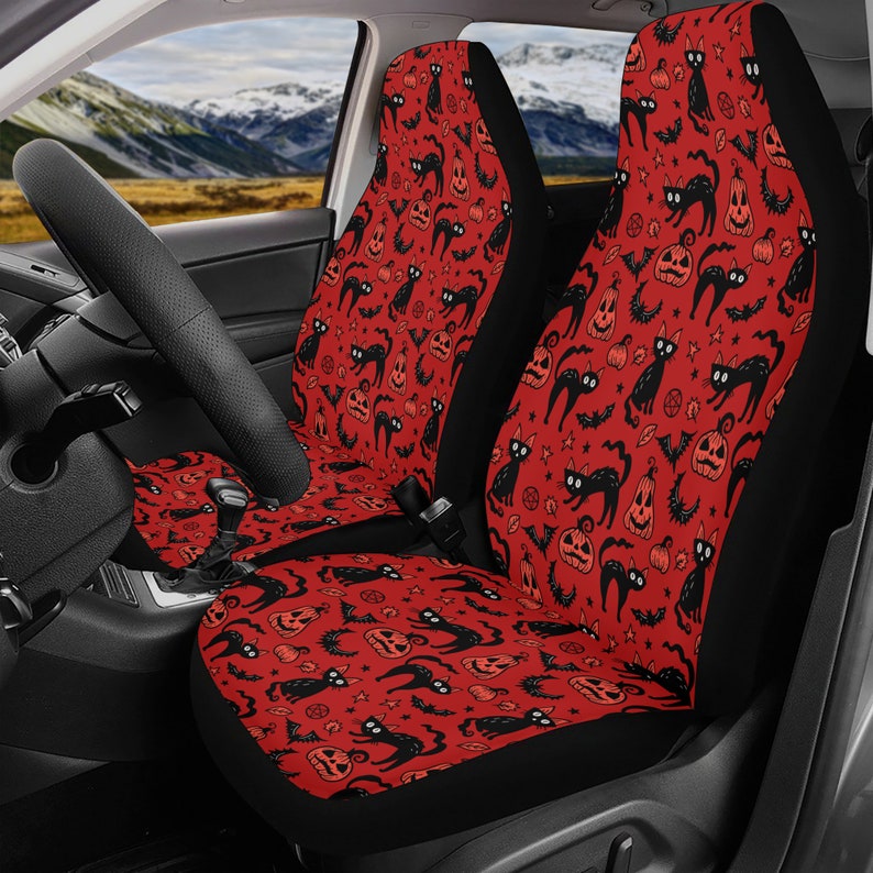 May include: Two red car seat covers with a black and orange Halloween pattern featuring black cats, pumpkins, bats, and stars.