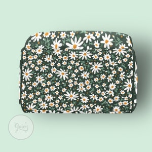 Peut inclure: Un sac fourre-tout en tissu vert fonc&eacute; avec un imprim&eacute; de marguerites blanches. Le sac a une fermeture &eacute;clair et une poign&eacute;e sup&eacute;rieure.