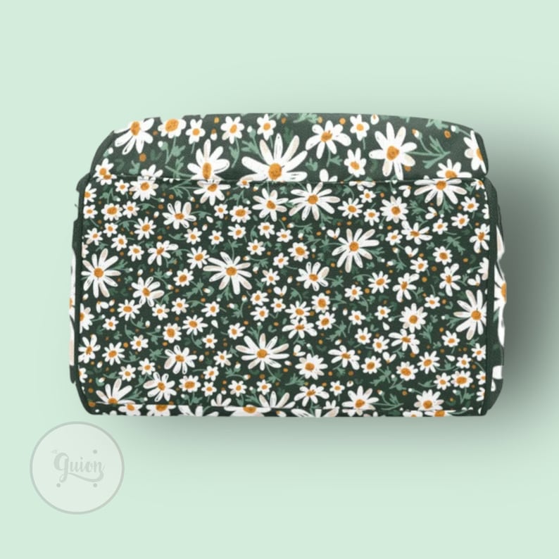 Peut inclure: Un sac fourre-tout en tissu vert fonc&eacute; avec un imprim&eacute; de marguerites blanches. Le sac a une fermeture &eacute;clair et une poign&eacute;e sup&eacute;rieure.
