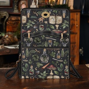 May include: A black leather bag with a zipper closure and a long adjustable strap. The bag has a whimsical design featuring illustrations of herbs, potions, and other magical elements.