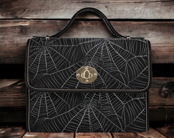 May include: A black leather handbag with a spiderweb pattern and a gold clasp.